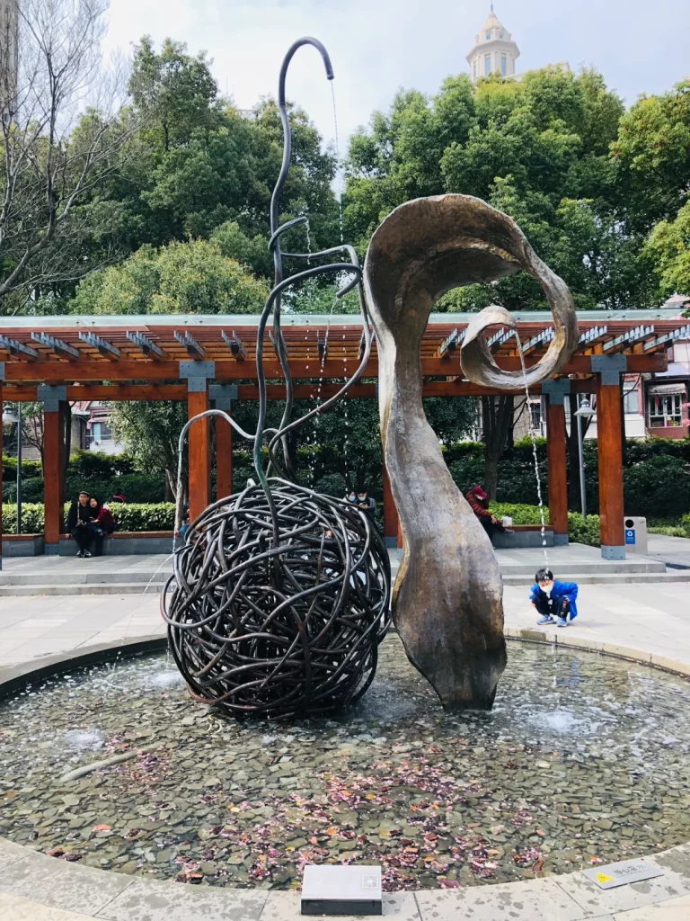 这个雕塑是美国女雕塑家芭芭拉・爱德斯坦的作品《生命之水》，它位于上海静安雕塑公园内。
作品用坚硬的金属来表现至柔的水，其中黑色藤条交织的球体与流畅弯曲的金属造型，正是艺术家以工业材质模拟水的流动与生命张力的体现。