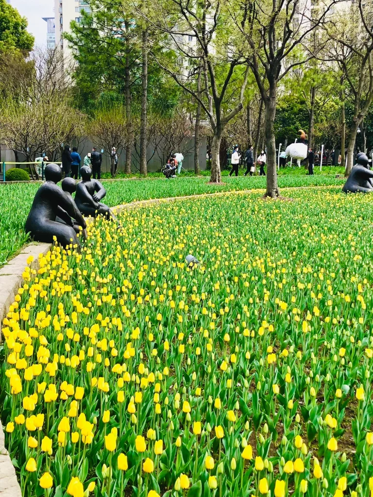 上海静安雕塑公园内的《悄悄话》（也被称为《和谐》或《晨》），它以抽象的黑色金属材质，塑造了一对情侣依偎而坐、轻声交谈的浪漫造型，与公园内的郁金香花海相互映衬，成为春日里颇具氛围感的打卡点。